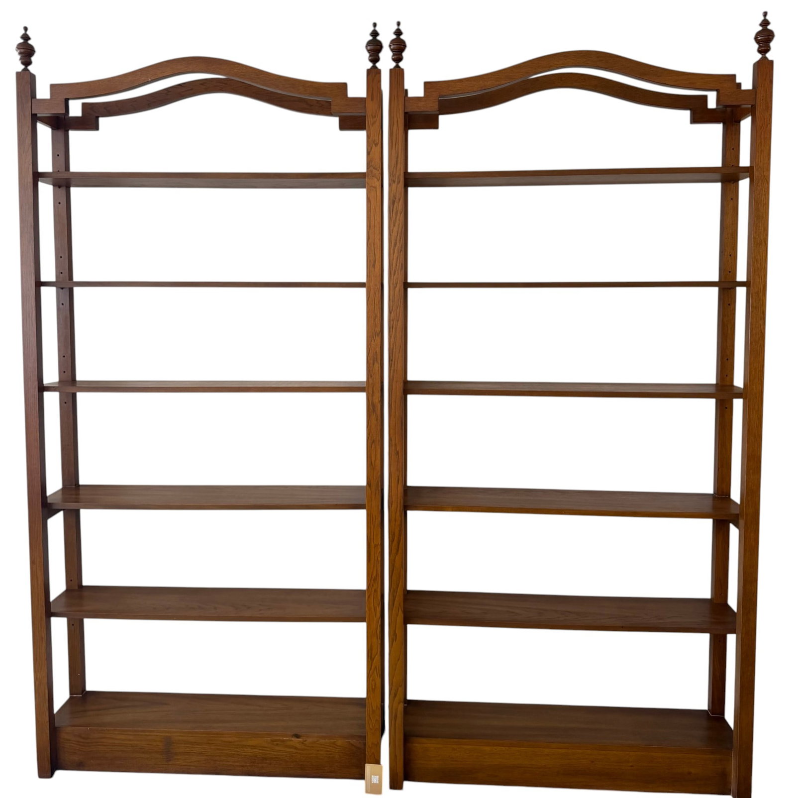 Pair of Traditional Arched Top Wooden Bookcases: A pair of traditional wooden bookcases, each featuring an elegant arched top with finial accents and six adjustable shelves. Crafted from what appears to be stained oak or a similar hardwood, these bo