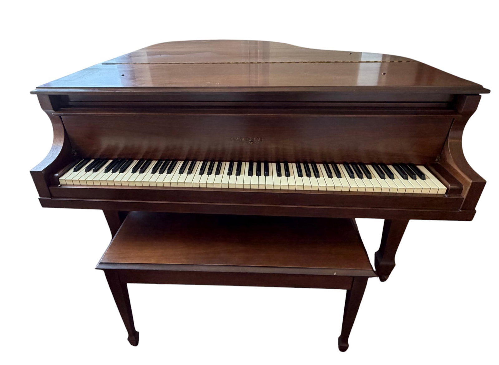 Kranich & Bach Baby Grand Piano with Bench: A Kranich & Bach baby grand piano, crafted with a rich, dark wood case. The piano features a full 88-key keyboard with white and black keys, along with three pedals. The lid can be propped open to enh
