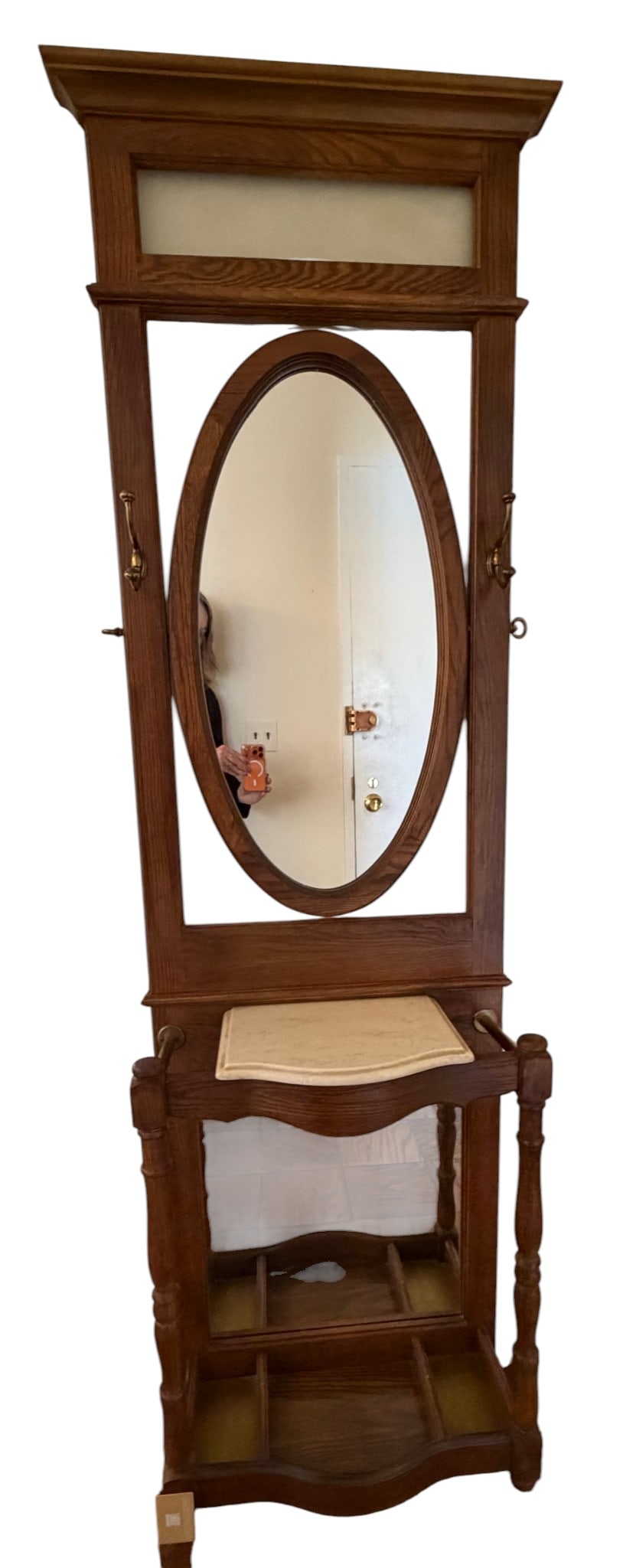 Victorian Oak Hall Tree with Mirror and Umbrella Stand: A charming late 19th-century Victorian hall tree crafted from oak, featuring a tall, rectangular frame with a decorative carved pediment at the top. The central oval mirror is flanked by a pair of bra