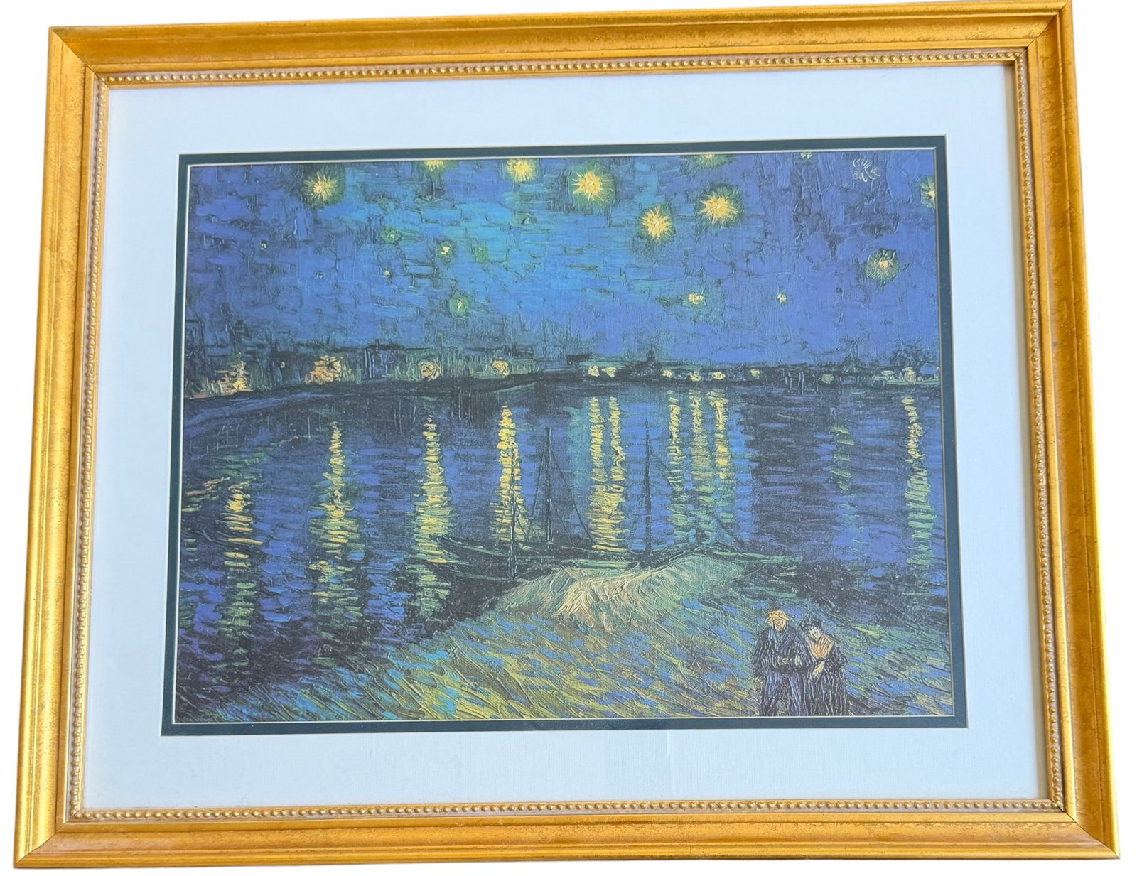 Framed Print of Van Gogh's "Starry Night Over the Rhone": A brightly colored print of Vincent van Gogh's iconic 1888 painting, "Starry Night Over the Rhone." The print features the characteristic impasto brushstrokes and vibrant blues, yellows, and greens