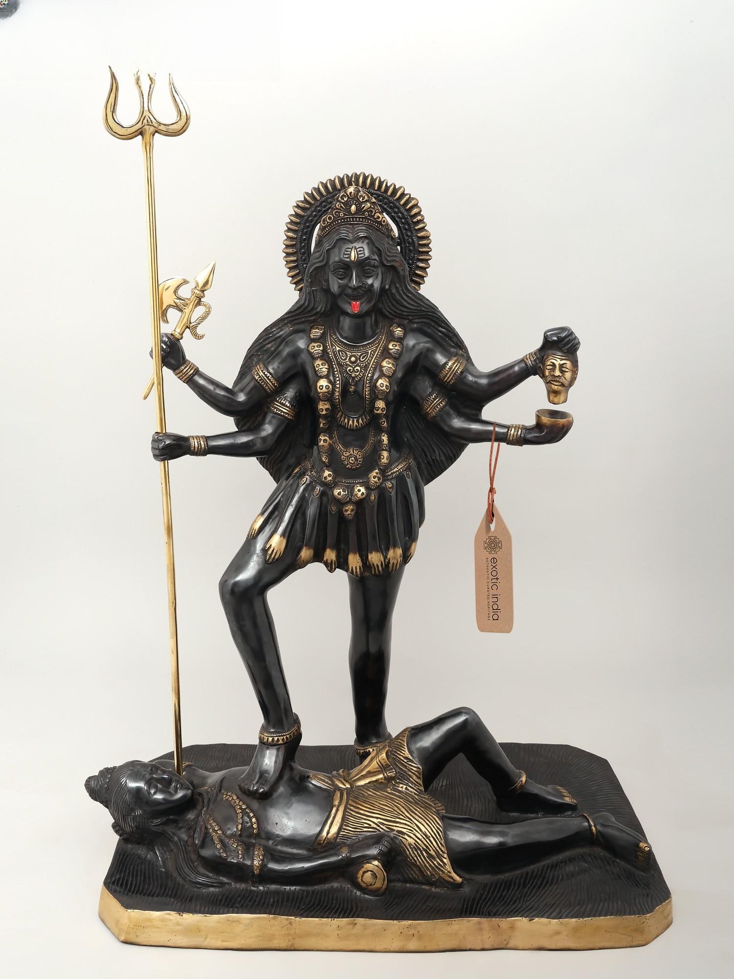 31" Large Goddess Kali Idol Standing on Lord Shiva | Brass Statue: Title: 31" Large Goddess Kali Idol Standing on Lord Shiva | Brass Statue Description: This Large Goddess Kali Standing on Lord Shiva statue is made of brass. It depicts Goddess Kali in the Chaturbhuj 