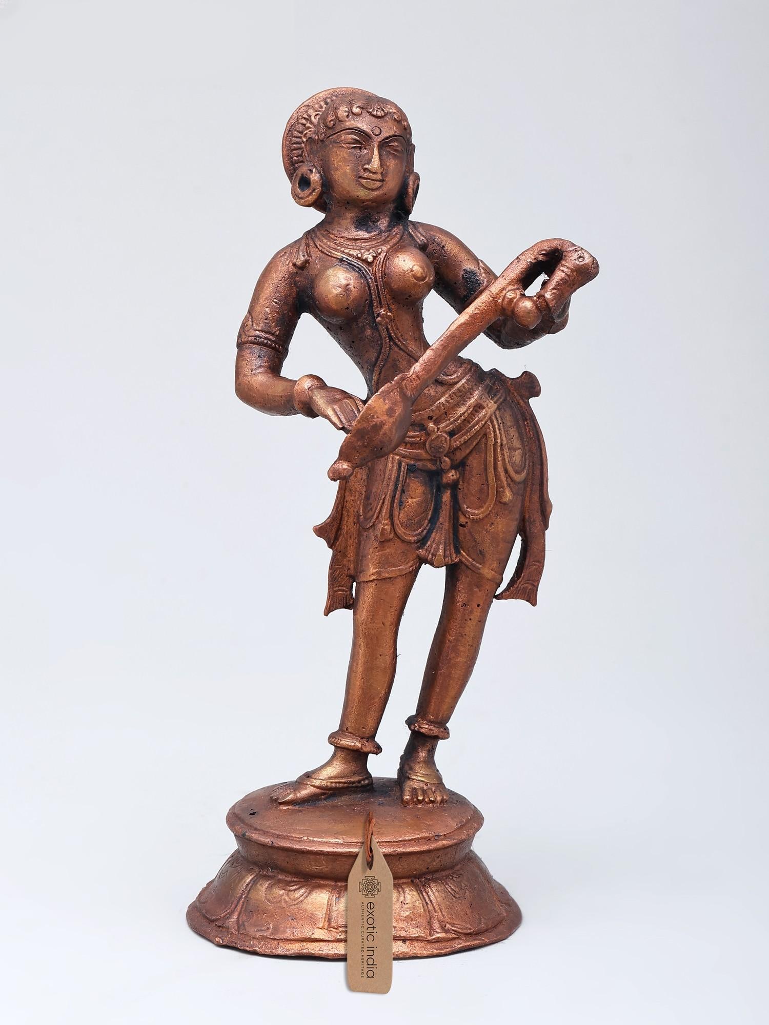 6" Small Copper Statue of Apsara Playing Musical Instrument: Title: 6" Small Copper Statue of Apsara Playing Musical Instrument Description: Apsaras, celestial nymphs in Hindu tradition, are celebrated as knowers of various arts, embodying grace and artistic