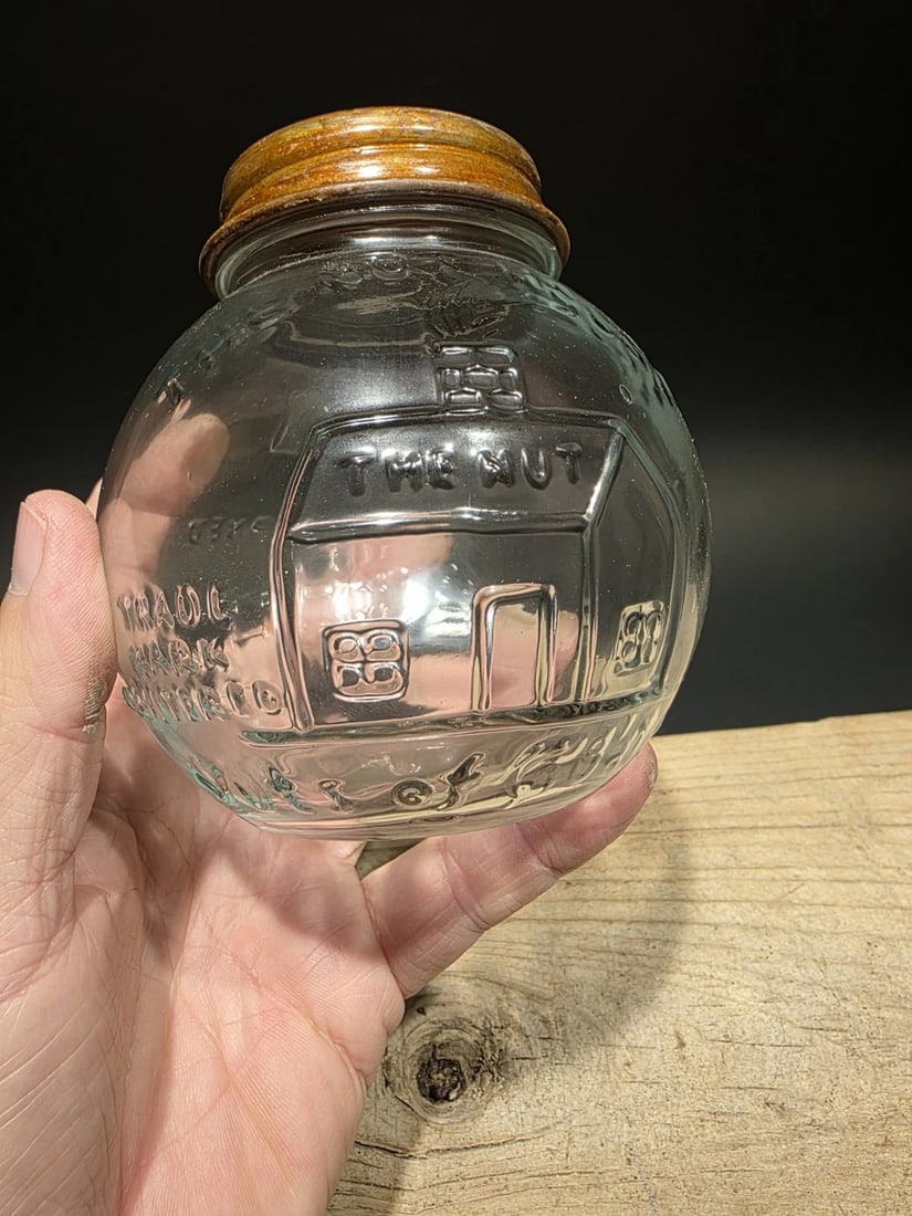 4 1/2" Glass Nut House Store Jar: 4 1/2" Antique reproduction "The Nut House" embossed glass store jar, originally used as a counter-top display jar for nuts. The jar features heavily embossed advertising, including a graphic of a hou