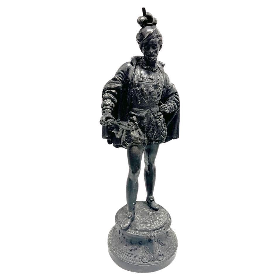 Spelter Cavalier Statue: Title: Spelter Cavalier Statue Description: A charming tabletop Spelter Cavalier statue captures the essence of an 18th-century French gentleman, adorned in a flowing cape and distinguished hat. Stand