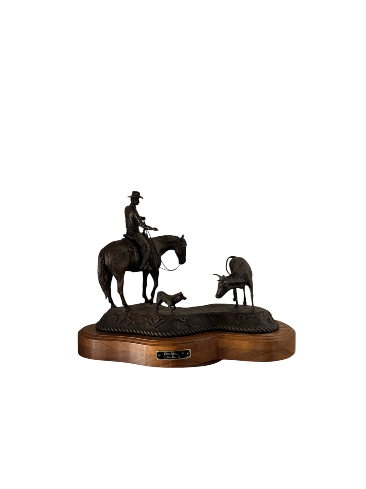 Ellen Moss, Bronze Sculpture, "Checking I.D.": This detailed bronze sculpture by Ellen Moss, titled "Checking I.D.," depicts a classic Western scene. A cowboy on horseback, accompanied by his dog, is shown with a steer. The bronze features a