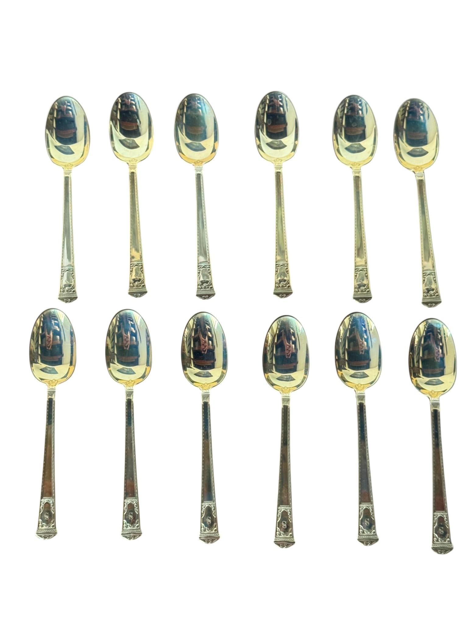 Set of Twelve Tiffany & Co. 14k Gold Demitasse Spoons in Original Roll: A exquisite set of twelve 14k gold demitasse spoons by Tiffany & Co., featuring a classic design with decorative handles. The spoons are presented in their original fitted felt roll, enhancing their