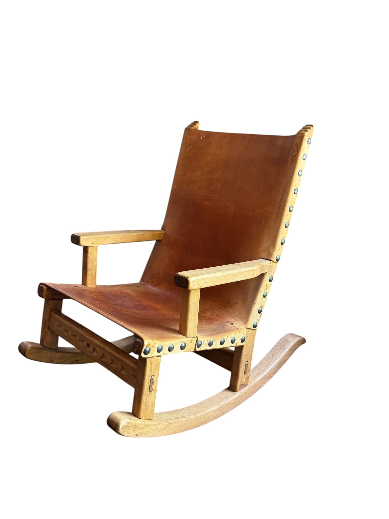 Mid-Century Modern Tan Leather and Wood Rocking Chair: A distinctive Mid-Century Modern-style rocking chair featuring a sturdy light-toned wooden frame and a suspended tan leather sling seat. The leather is secured to the frame with brass-toned studs,