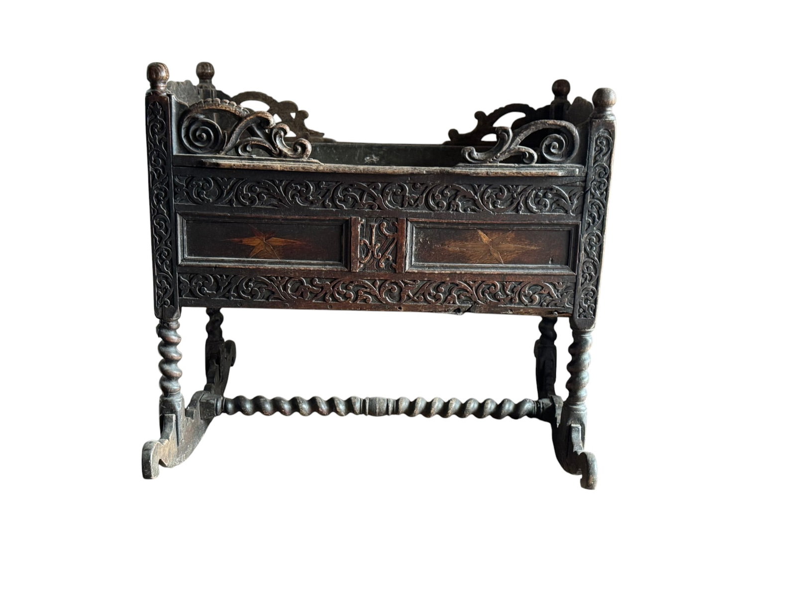Carved Continental Baroque Style Cradle, Likely 17th or 18th Century: This intricately carved wooden cradle features a distinct Continental Baroque style, likely dating from the 17th or 18th century. The cradle is crafted from a dark, probably oak or walnut, wood and