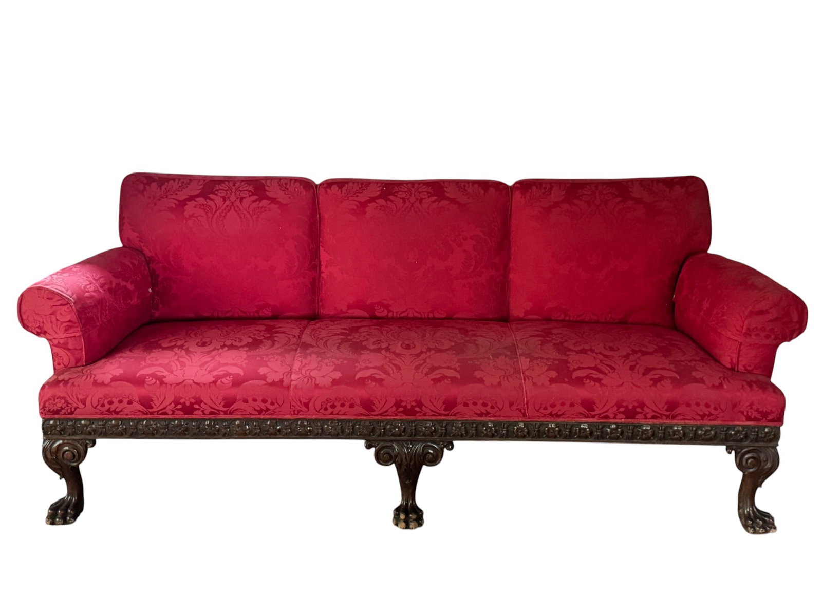 Carved Mahogany Sofa with Red Damask Upholstery: A substantial carved mahogany sofa, likely English, late 19th or early 20th century. The sofa features a robust frame with highly ornate carving along the skirt and rising into cabriole legs