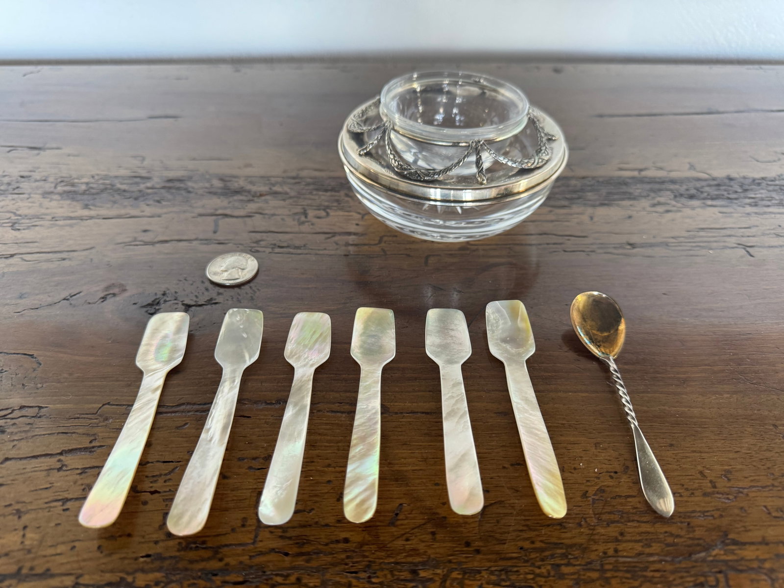 Fabergé Mother-of-Pearl Caviar Set with Silver-Plated Accents: This elegant Fabergé caviar set features a clear glass caviar server with a silver-plated rim, intricately decorated with a rope and garland motif. The set includes a full complement of six