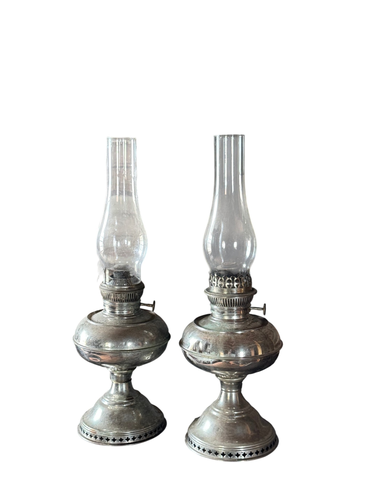 Pair of Victorian Silver-Plated Kerosene Lamps: A matching pair of Victorian-era silver-plated kerosene lamps, featuring ornate bases and clear glass chimneys. The lamps exhibit classic styling from the late 19th to early 20th century, consistent