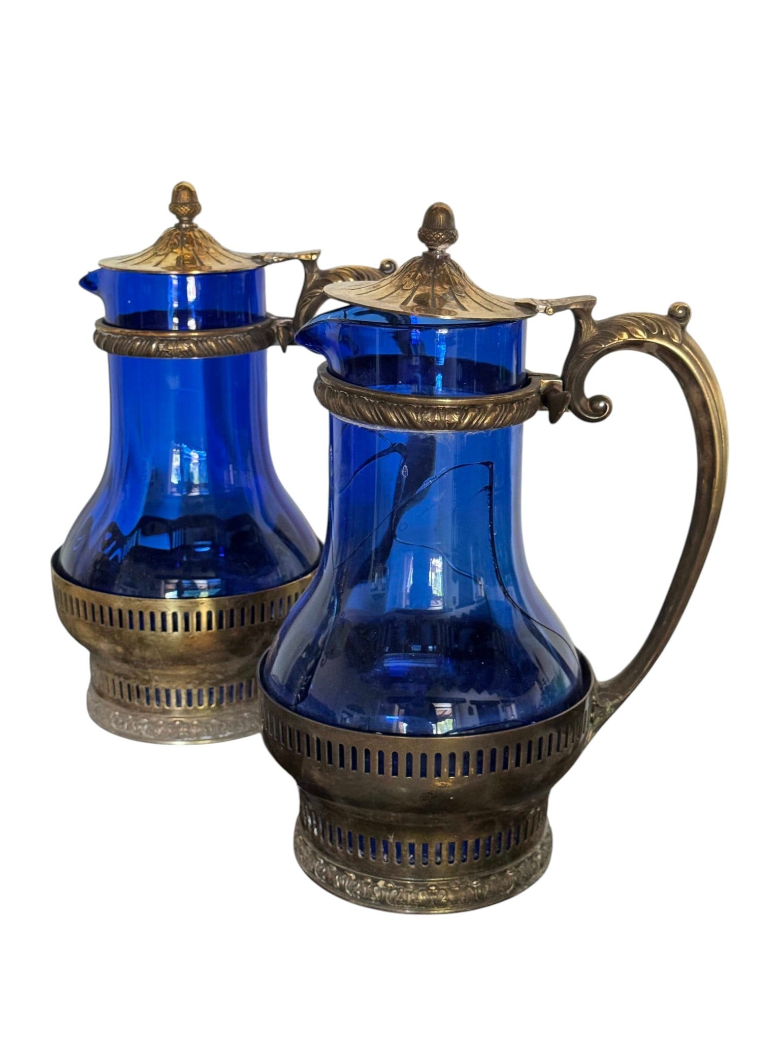 Pair of 19th Century Gorham Enameled Cobalt Blue Glass and Gilt Metal Ewers/Decanters: A striking pair of late 19th-century ewers or decanters, crafted from vibrant cobalt blue glass. The glass bodies are intricately enameled with delicate floral motifs in white and gold, a testament