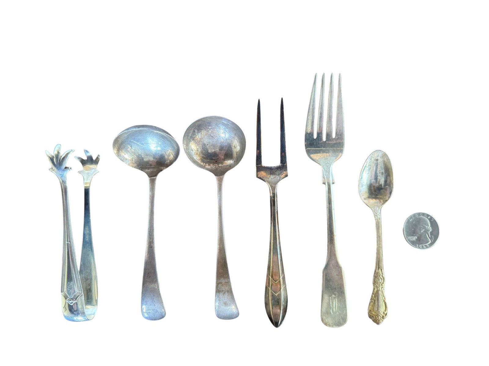 Collection of Antique Sterling Silver Utensils: This lot features a curated collection of six antique sterling silver serving utensils, showcasing a range of styles and functions. The collection includes a pair of sugar tongs, two small ladles, a