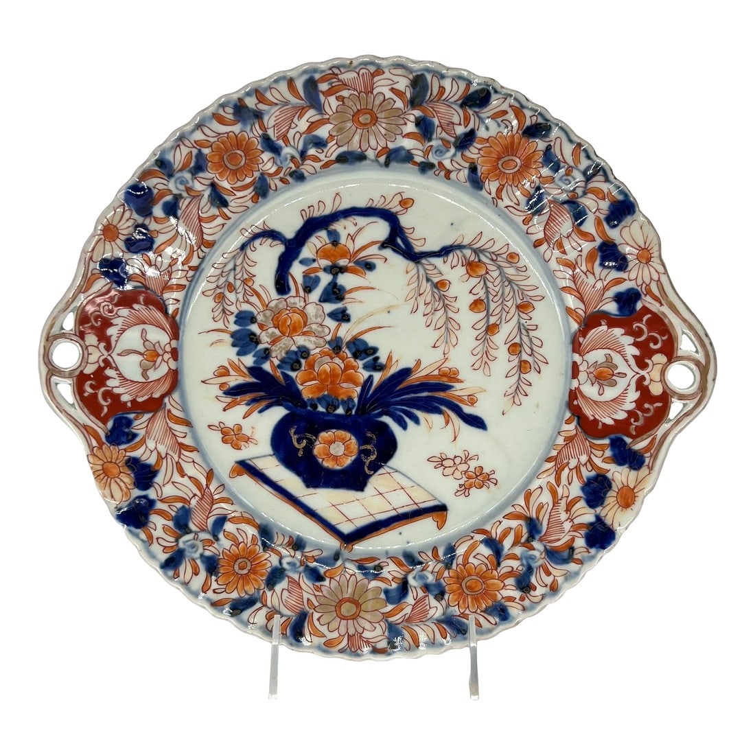 Antique Japanese Imari Decorated Pierced Handled Platter: An antique Japanese porcelain Imari pattern platter. The platter is decorated with orange, red, blue and gold tone floral / foliate motifs to the edges. Which surround a central bonsai tree