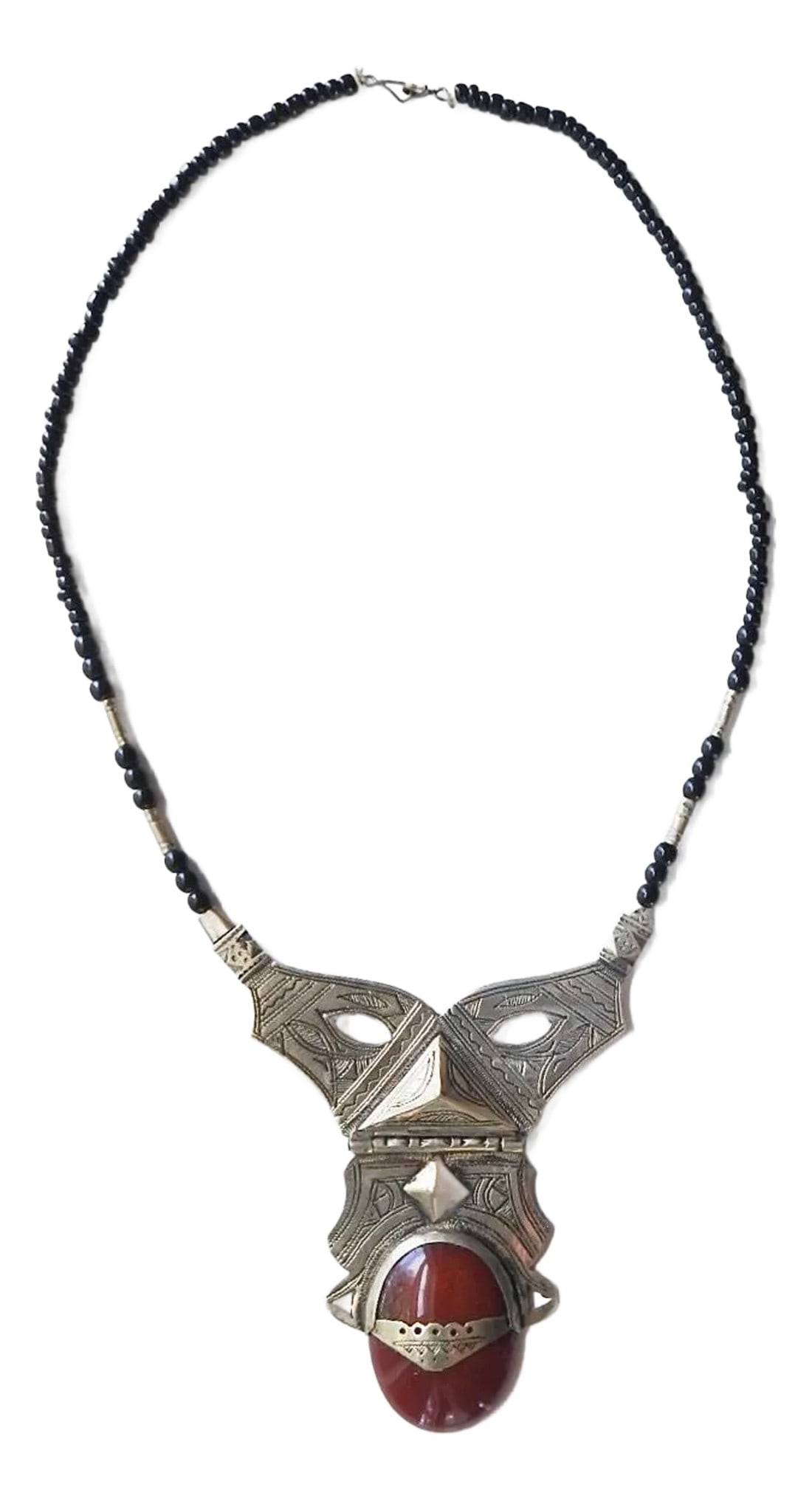 Vintage Tribal Carnelian and Silverplate Necklace: Vintage mid 20th century Tuareg silverplate necklace with carnelian cabochon stone and black glass beads. Large hinged pendant is engraved with detailed linear design, small hook closure. Overall mino