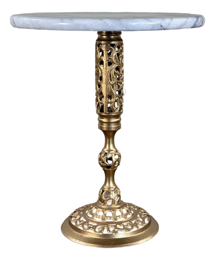 Vintage French Neoclassical Marble Top Brass Pedestal Side Table With Pierced Base: This vintage pedestal side table features a round white marble top with subtle gray veining set on an ornate cast brass pedestal base with pierced neoclassical scrollwork detailing. The combination of