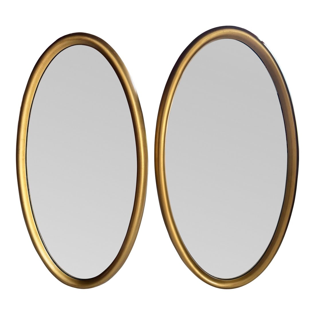 Matching Pair of Mid 20th Century Giltwood Oval Wall Mirrors - 20" X 38": A matched, heavy pair of mid-century modern oval wall mirrors featuring a substantial, 2-inch deep carved wood frame with a rounded profile. The finish is a hand-applied metallic gold leaf with a
