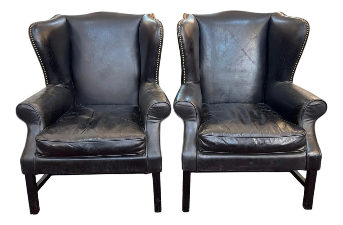 Pair of Vintage Black Leather Wingback Chairs With Brass Nailhead Trim: Stylish pair of vintage wingback chairs upholstered in black leather. Features classic high backs, gently rolled arms, and decorative brass nailhead trim for a timeless look. Comfortable and
