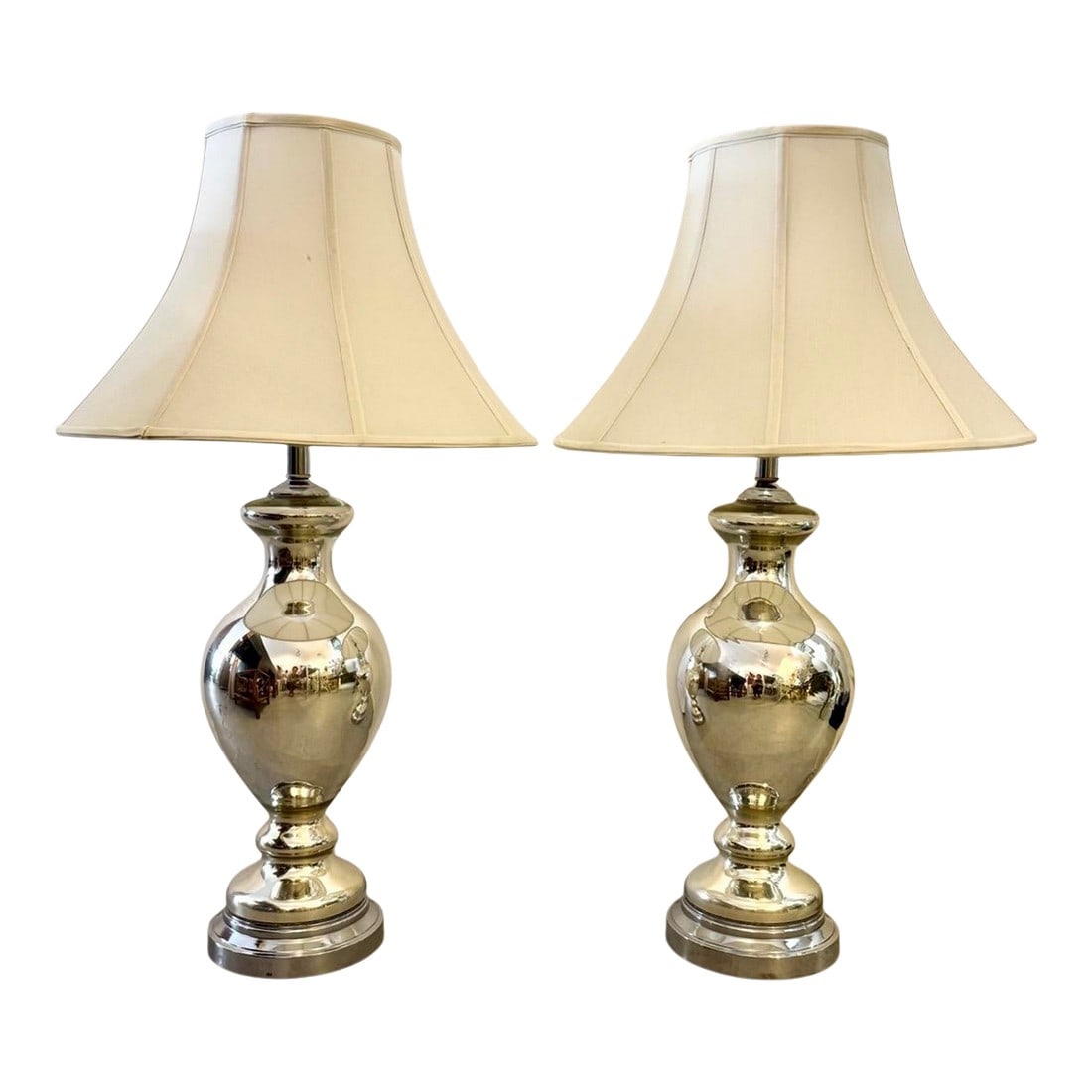 Mid 20th Century Hollywood Regency Mercury Glass Table Lamps - a Pair: These vintage mercury glass table lamps feature a classic urn-shaped base with a shimmering, mirrored finish typical of the mid-20th-century aesthetic. This reflective glass, often called "mercury gla