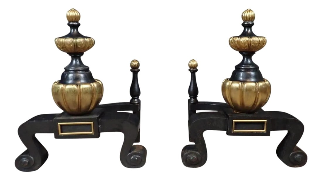 Pair of 19th-Century French Neoclassical Black and Gilt Chenets / Andirons: This handsome pair of 19th-century chenets exemplifies French Neoclassical style, featuring bold sculptural forms paired with refined decorative details. Each chenet rests on a sturdy black