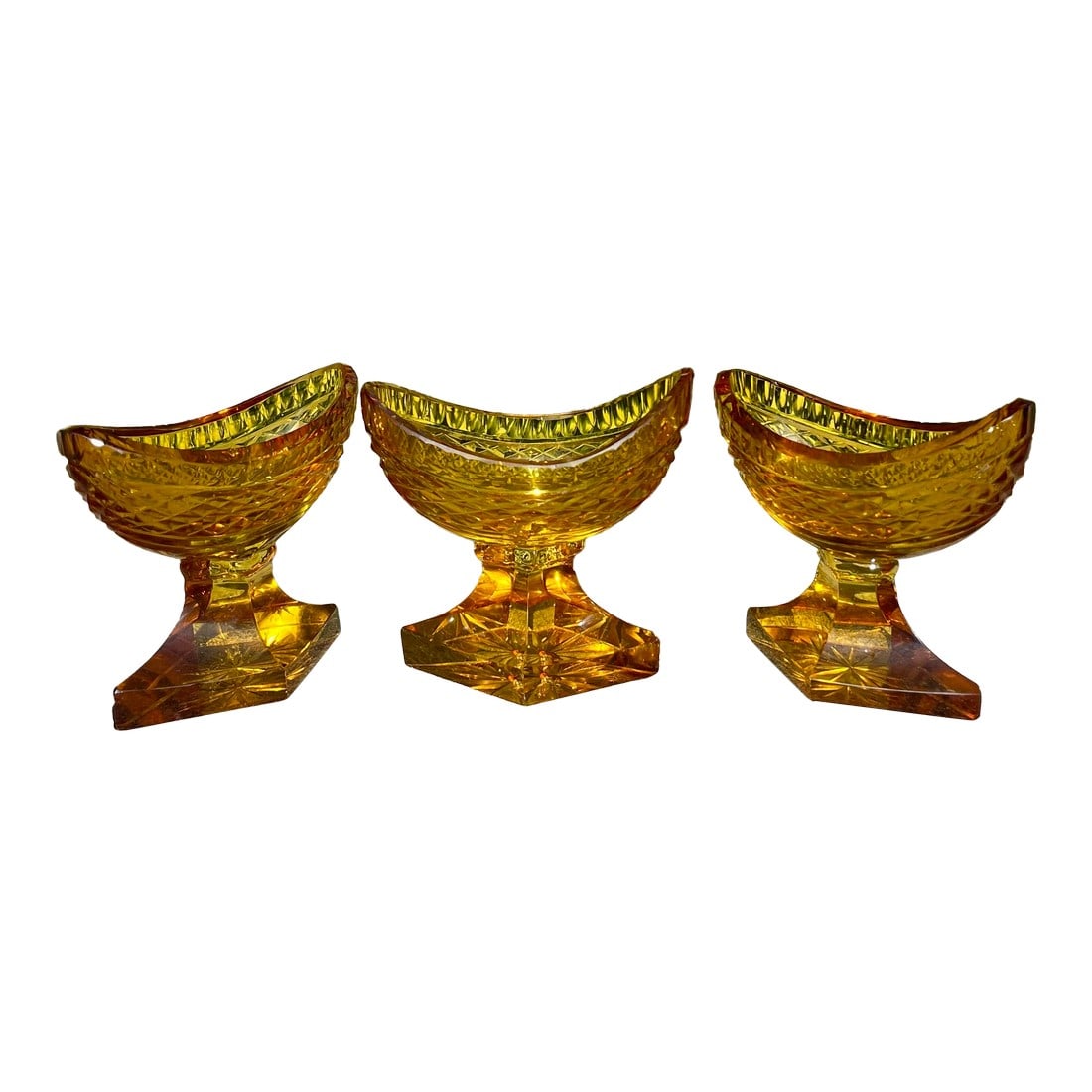 (3) Antique Anglo-Irish Cut Crystal Amber Glass Salt Cellars: Features a navette (boat) shape with an intricate diamond cut pattern across the body and supported by a stepped diamond pedestal base. Intricate star cut design on the underside. C. 19th Century,