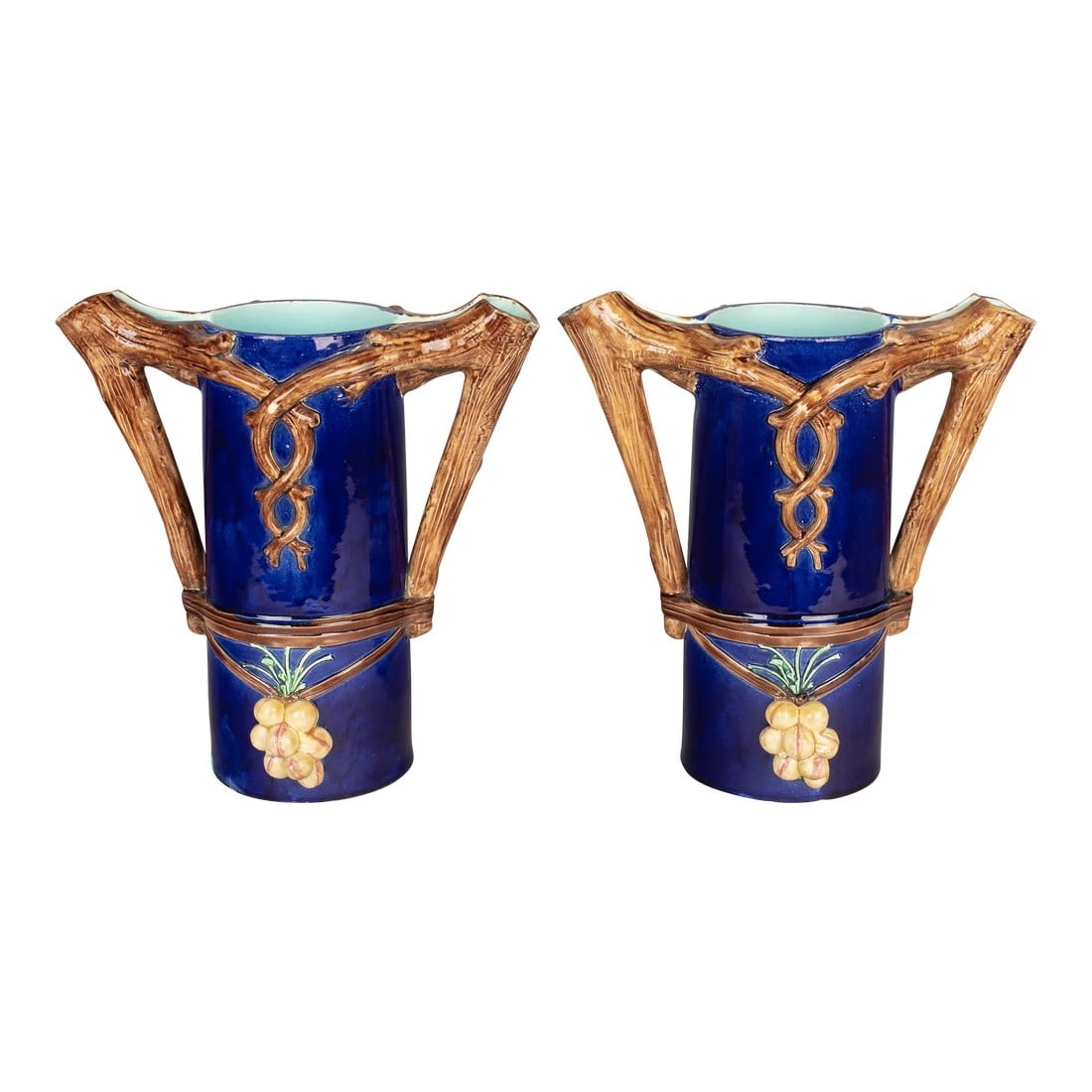 1920s French Majolica Pitchers or Vases - a Pair: A pair of French Majolica vases or pitchers, each with double tree branch form handles and spouts. Deep, rich cobalt blue glaze with aqua interior and grape clusters. Minor glaze loss. Condition: Alte