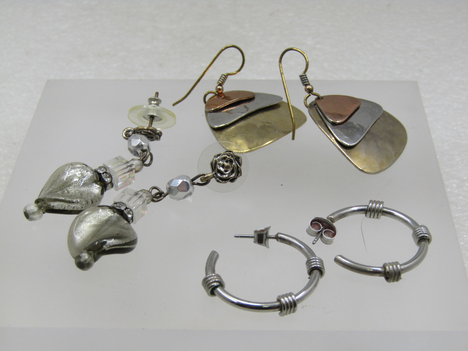 3 Pair of Pierced Earrings, Drop, Dangle, Hoops, 1980's-1990's: 3 Pair of Pierced Earrings, Drop, Dangle, Hoops, 1980's-1990's. Tri-colored hammered drop earrings that are in copper, silver, and gold tone and appx. 1.5" from curve in hold tone hoop post that has a