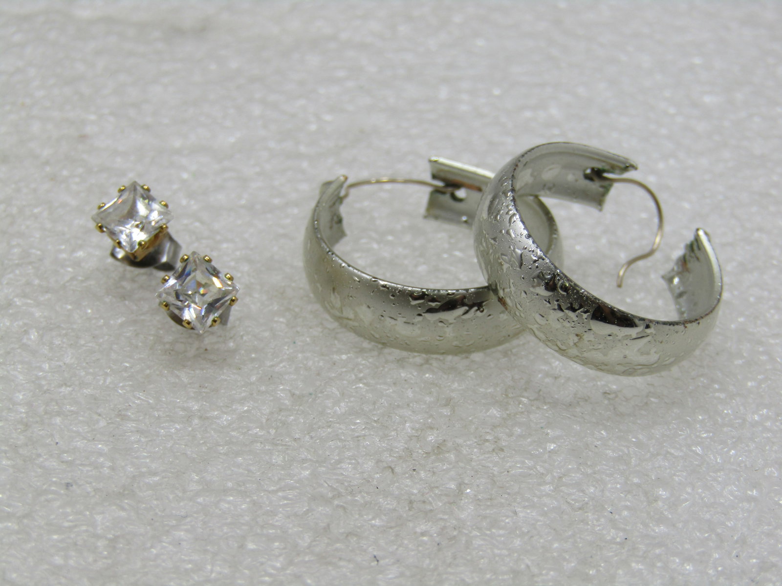Two Pair of Pierced Earrings, CZ Studs & Hoops: Two Pair of Pierced Earrings, CZ Studs & Hoops. The hoops have a satiin texture on the out side of the domed hoop and are appx. 1", silver tone. The studs are appx. 4.8mm square clear cz prong-set sto