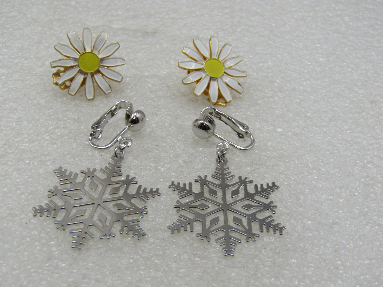 Vintage Daisy & Snowflake Earrings. Clip, 2 Pr.: Vintage Daisy & Snowflake Earrings. Clip, 2 Pr. Silver Tone Snowflake Signed Avon, 1.5" long and 1" wide. Yellow & white enameled daisy stud clip earrings, gold tone. Not signed. A pair for two season