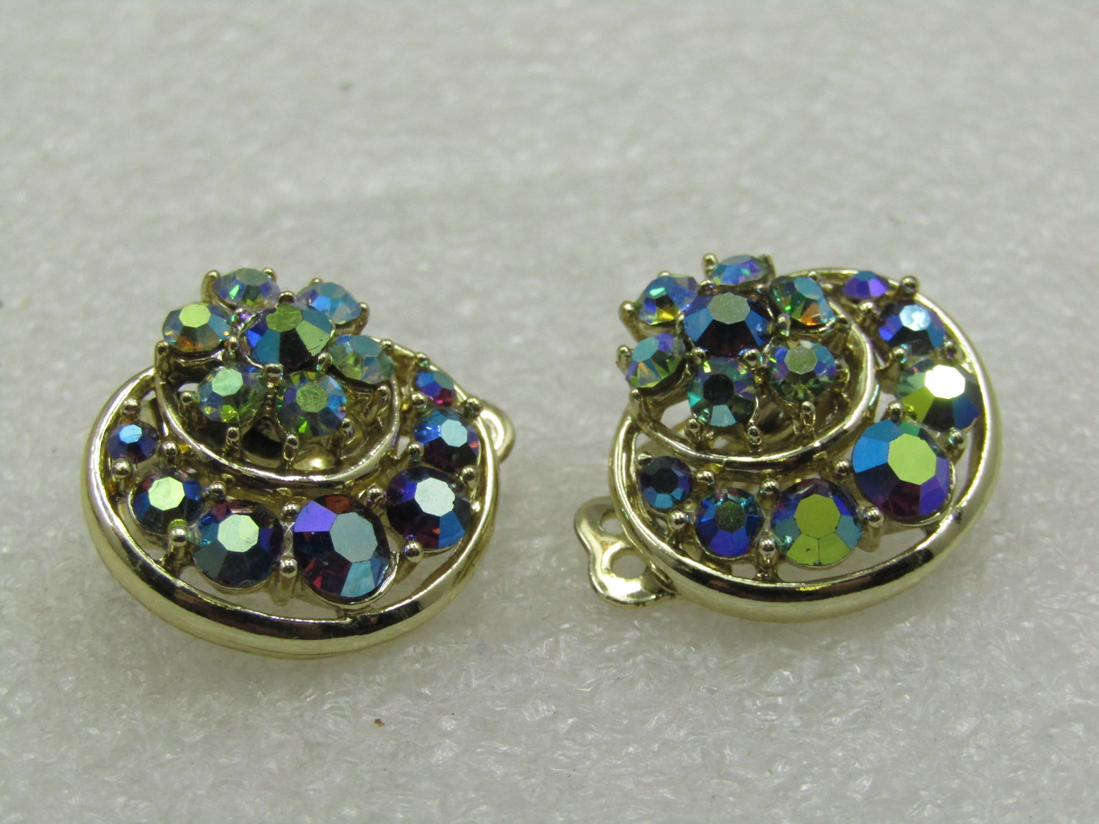 Vintage Peacock Aurora Borealis Rhinestone Clip Earrings, Mid-Century: Vintage Peacock Aurora Borealis Rhinestone Clip Earrings, Mid-Century, Gold Tone with a curved section with graduated rhinestones and a blossom. They are appx.7/8" slight oval shape. They arenot signe