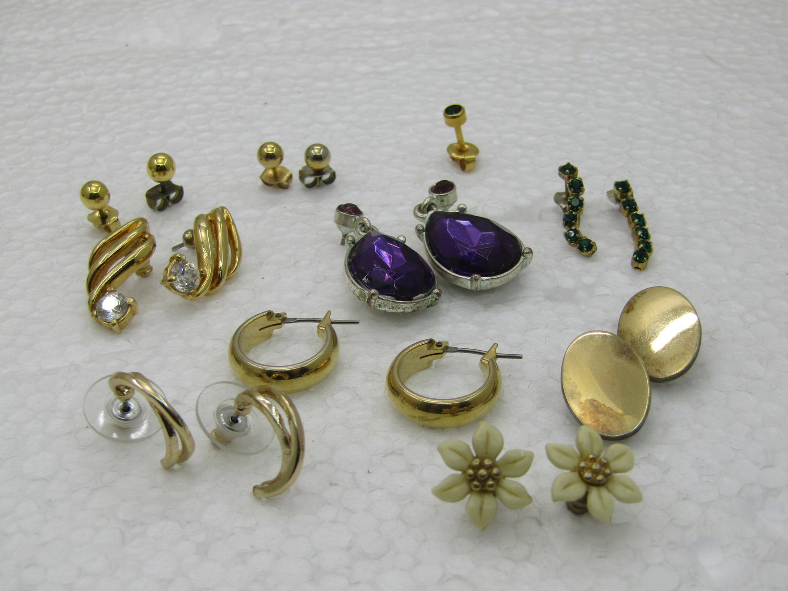 9 Pierced Earrings Pairs, 1 Single Earrings, Hoops, Studs, +: 9 Pierced Earrings Pairs, 1 Single Earrings, Hoops, Studs, +, gold ball studs, gold hoop, gold oval studs, Amethyst Rhinestone Drops, Green Rhinestones, white floral, see photos. There is a single stu