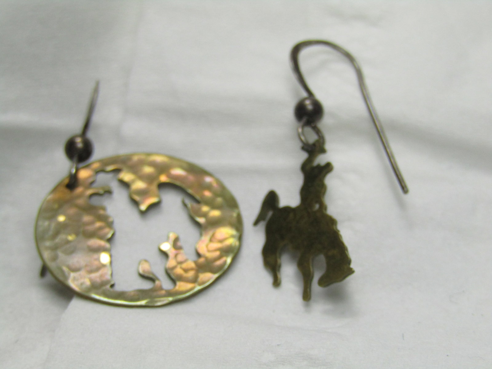 Vintage Rodeo Hammered Brass Earrings, Pierced: Vintage Rodeo Hammered Brass Earrings, Pierced. One earrings is a nearly 3/4" circle with a cutout of a cowboy and bucking horse, and the other is the piece that was cut out. They have a hammered bras