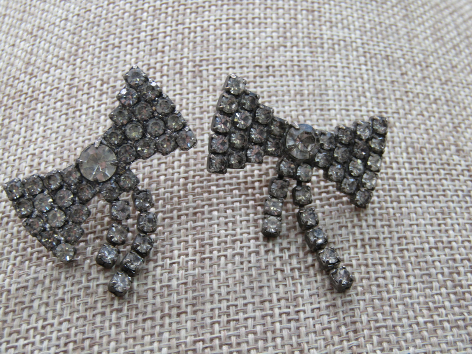 Vintage Rhinestone Bow Pierced Earrings, Dangling Tails, 1.25": Vintage Rhinestone Bow Pierced Earrings, Dangling Tails, 1.25". Black background with a 1.25" wide rhinestone bowtie design with larger rhienstone in the center and two rhinestone ribbon bow tails