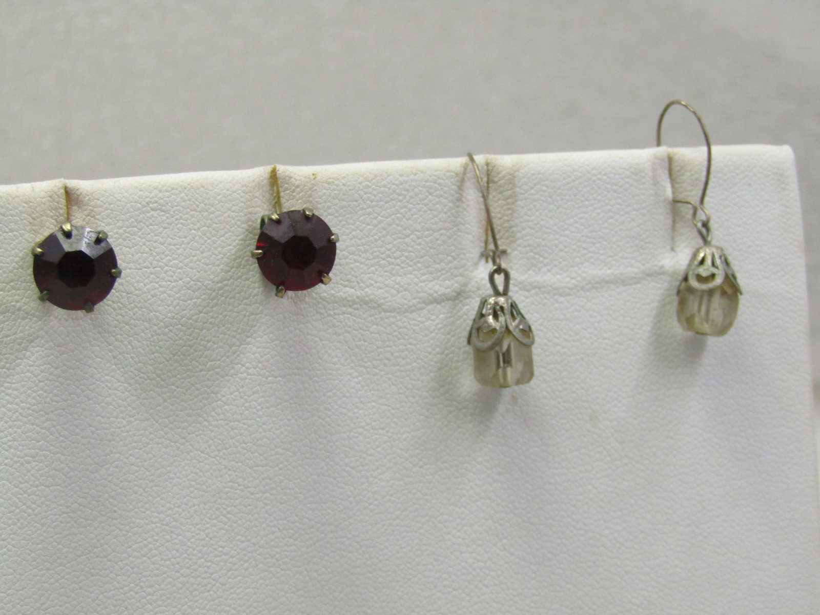 2 Pair Vintage Crystal Earrings, Pierced, 1950's-1960's: 2 Pair Vintage Crystal Earrings, Pierced, 1950's-1960's. One pair is an 8mm red rhinestone stud set in a gold tone pronged basket. The other pair is a clear faceted crystal with silver plated filigree
