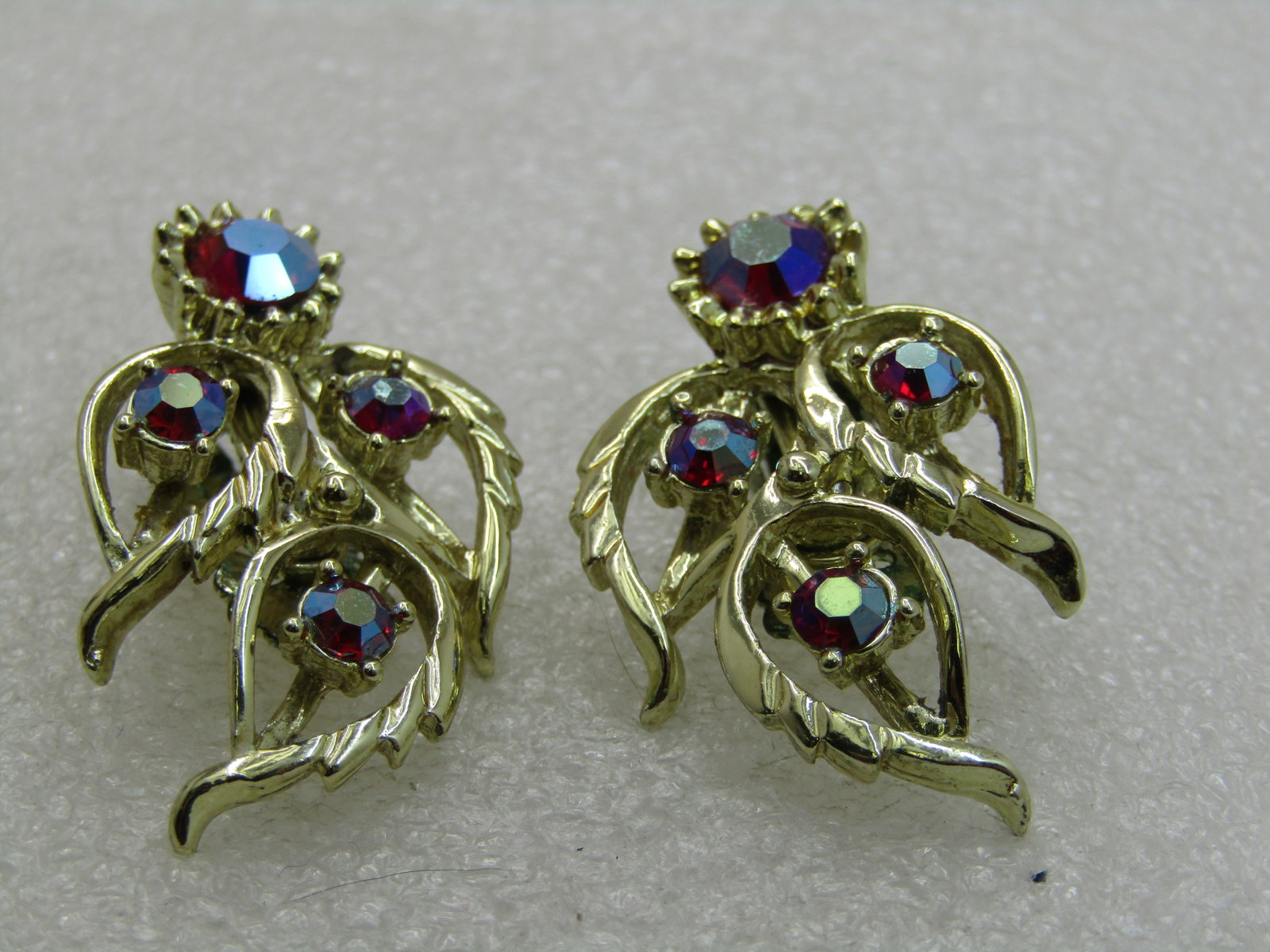 Vintage Judy Lee Red Rhinestone Earrings, Clip, Aurora Borealis: Vintage Judy Lee Red Rhinestone Earrings, Clip, Aurora Borealis in red with shimmering rainbow hues. Open leaf design with rhienstones in the center of each leaf and a larger one at the back. The