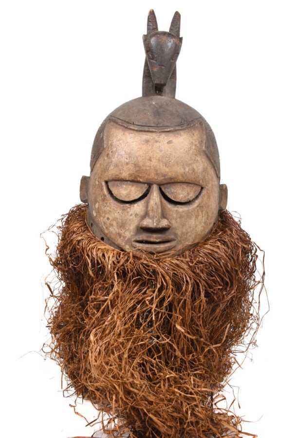 Helmet Mask – Wood, Raphia – Suku – Congo: Worn during male initiation ceremonies, masks like these represented all departed ancestors. Mourning songs were sung during the ritual; the vertical lines on the face are tears. Neighbors of the
