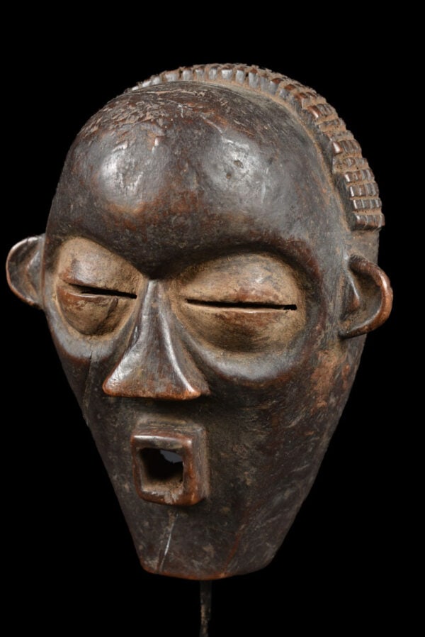 Face Mask – Wood – Mbagani – Congo: Wooden PENDE mask from former Belgian Congo. Nice aged patina in good condition with traces of tribal use. The mask is decorated with a full raphia on top of the head. Provenance: former private