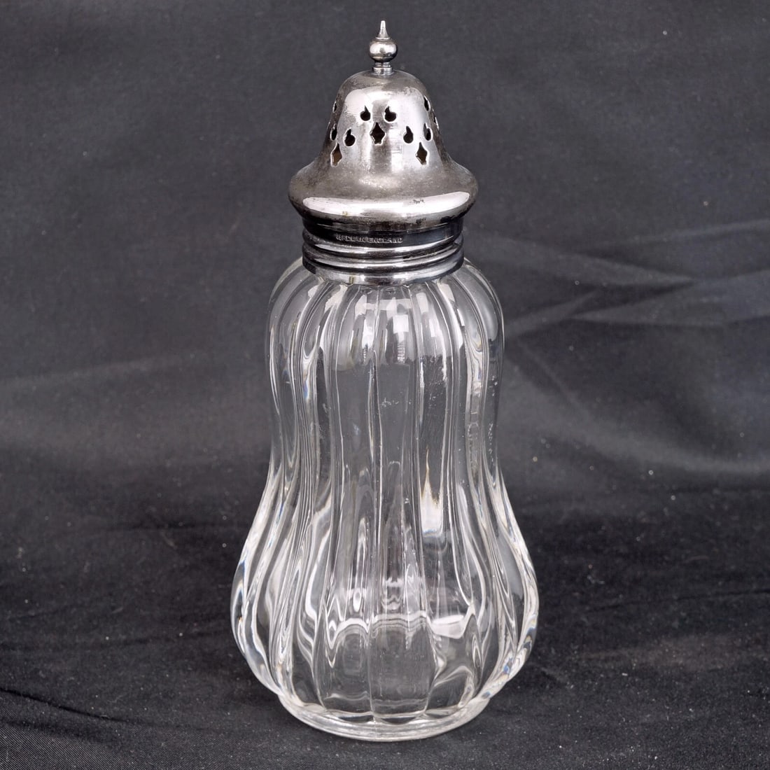 English Silverplate/Glass Sugar Shaker c 1930: Title:English Silverplate/Glass Sugar Shaker c 1930 Size:2 ¾” diameter x 6 ½” tall. Description:An English sugar shaker with a silver plate top that will be useful for