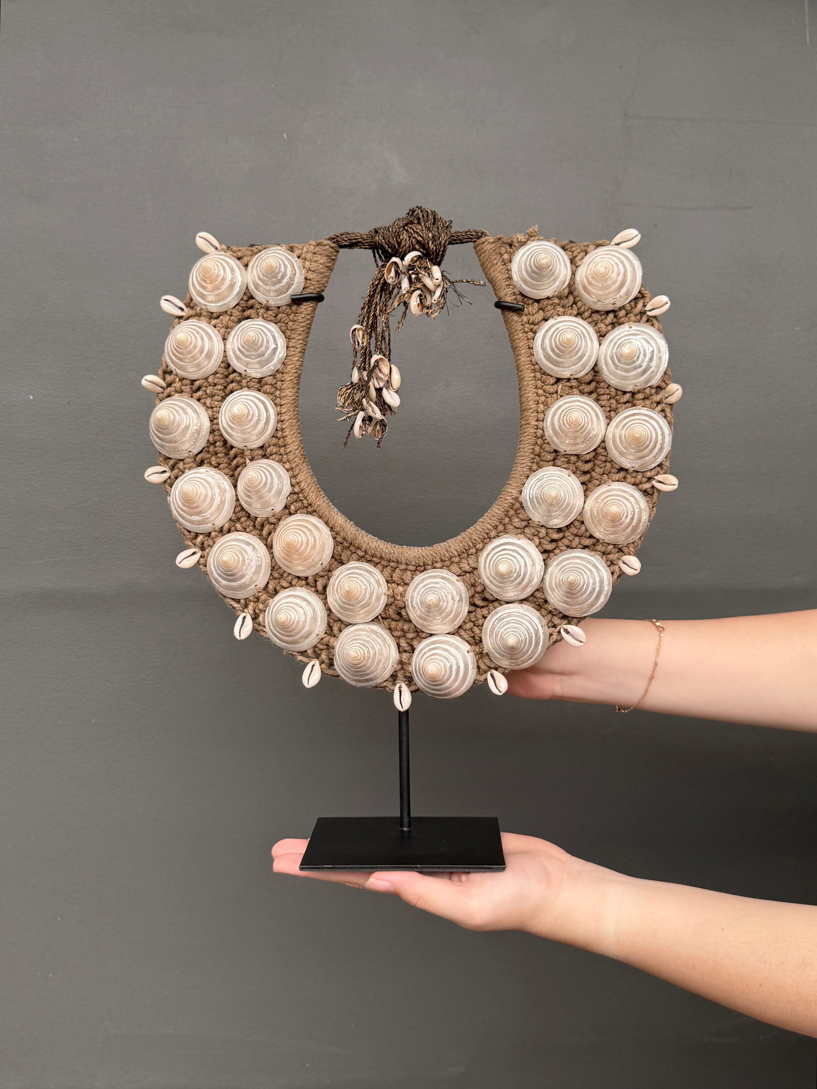Decorative shell necklace on a custom stand: Title: Decorative shell necklace on a custom stand Maker:Unknown Origin: Indonesia Date/Period:2026 Materials:Shells, natural fibers, steel Dimensions:Height including stand: 39 cm / 15.3 inches