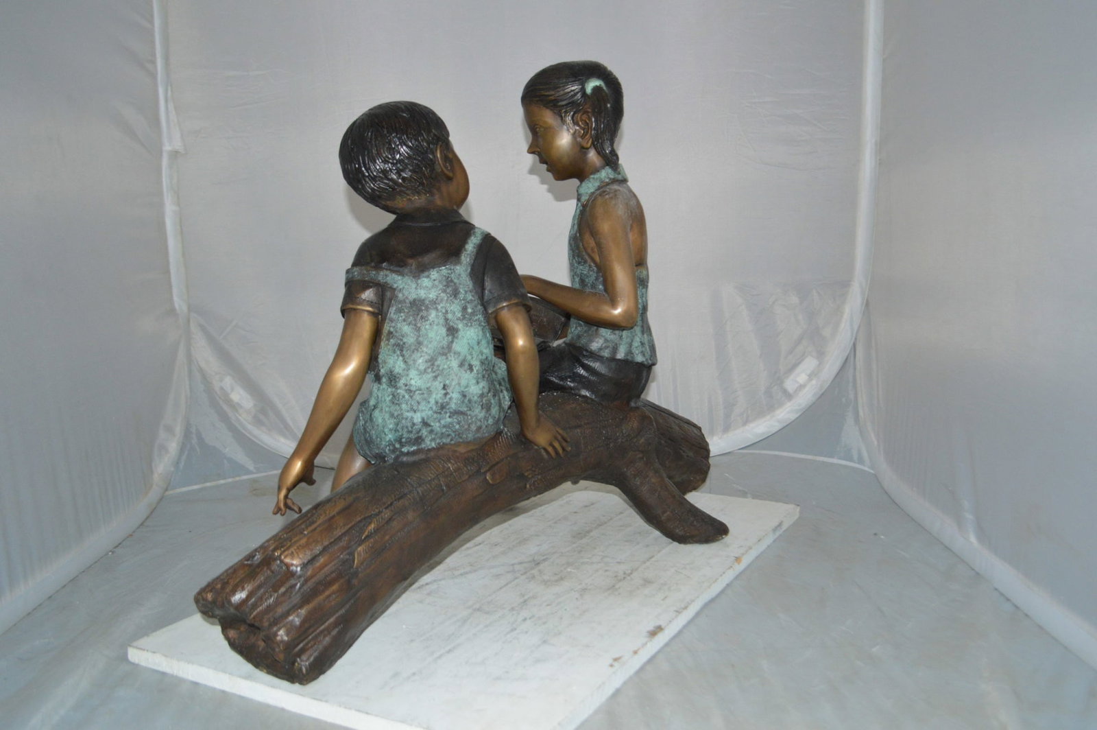 Boy and Girl on a tree log reading Bronze Statue - Size: 37"L x 14"W x 27"H. - 10
