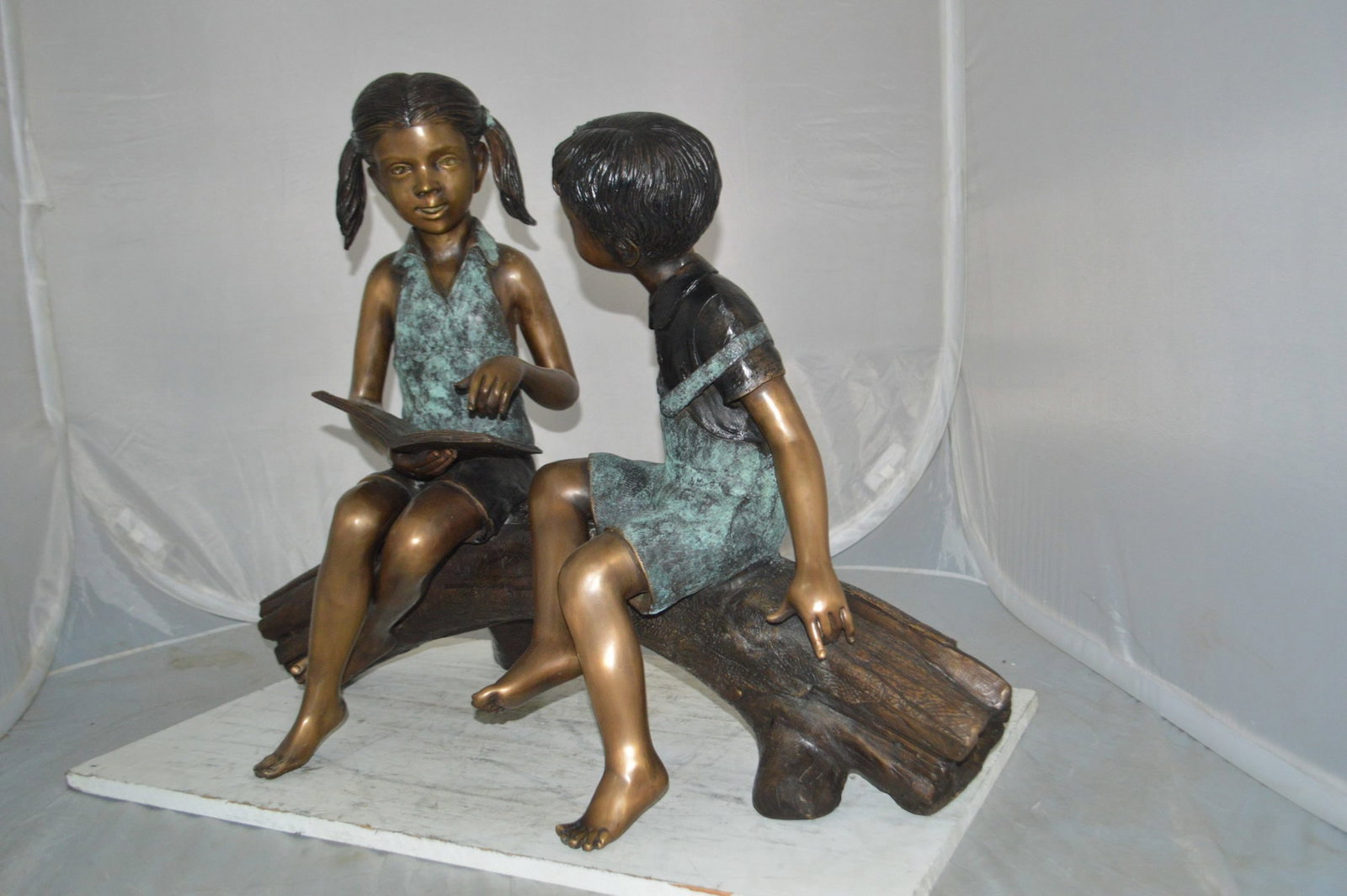 Boy and Girl on a tree log reading Bronze Statue - Size: 37"L x 14"W x 27"H. - 12