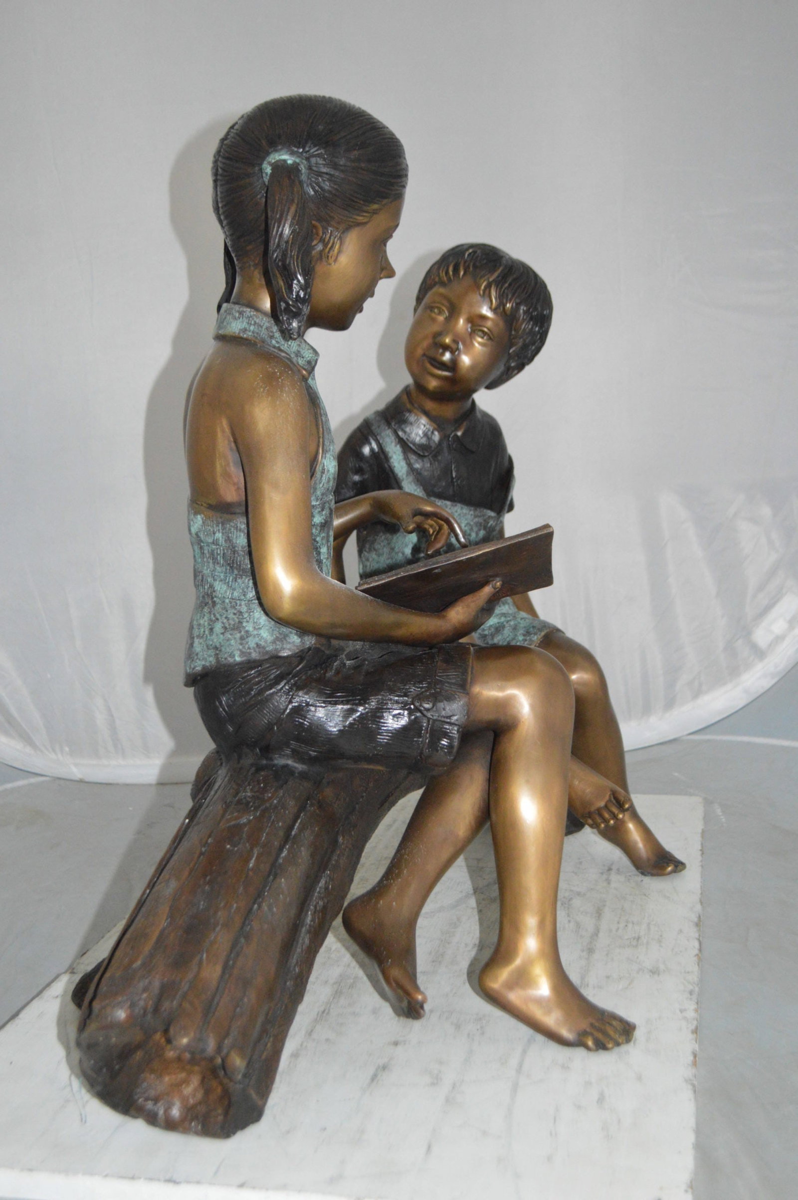 Boy and Girl on a tree log reading Bronze Statue - Size: 37"L x 14"W x 27"H. - 7