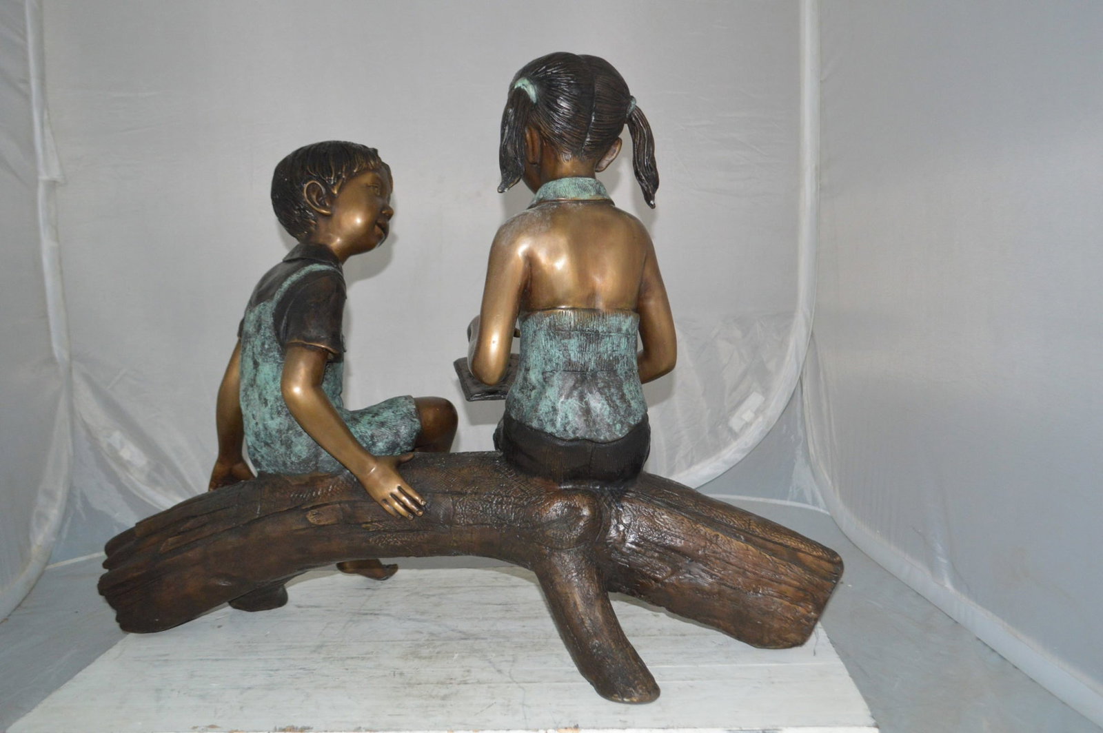 Boy and Girl on a tree log reading Bronze Statue - Size: 37"L x 14"W x 27"H. - 9
