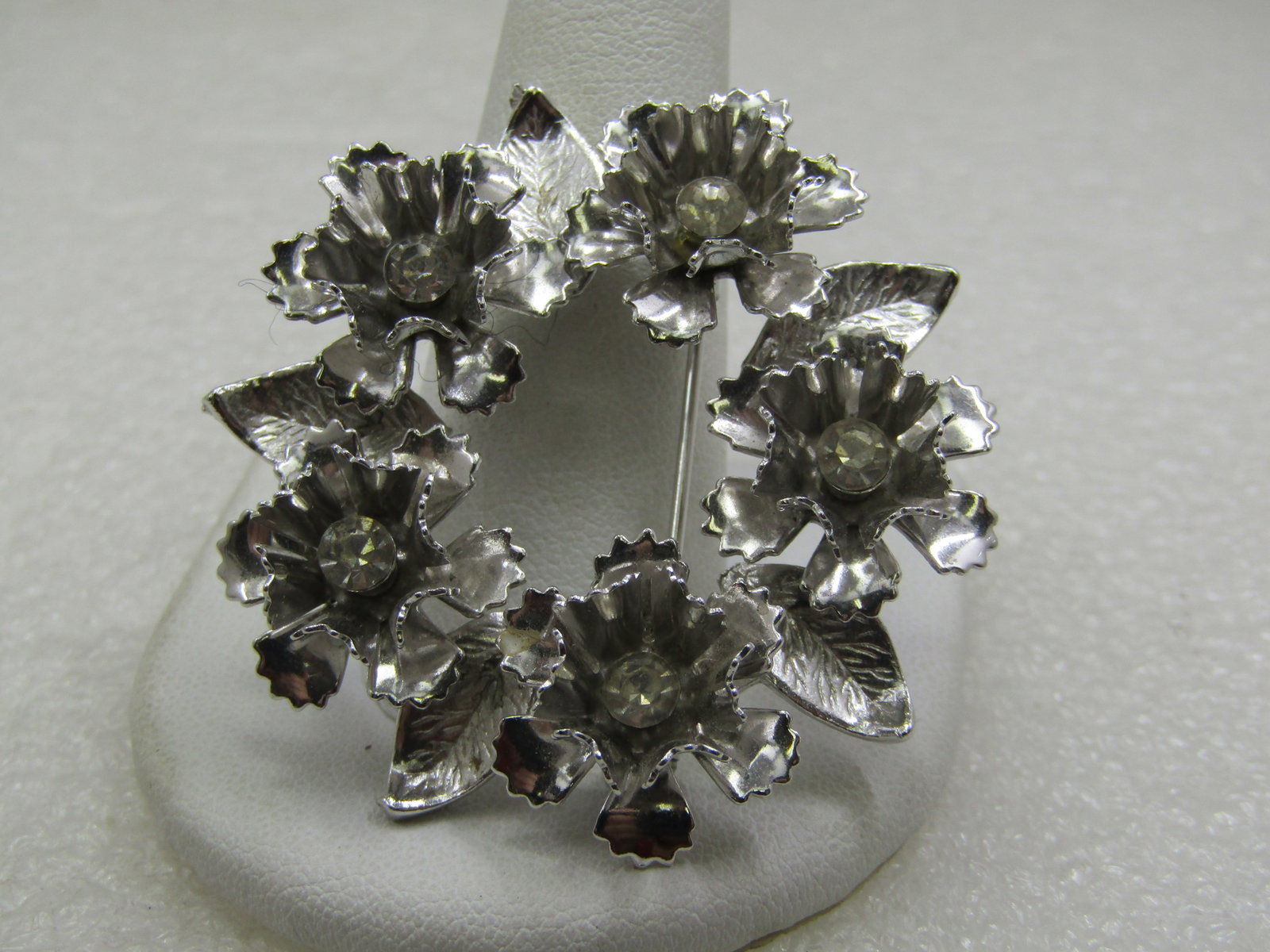 Vintage Floral & Rhinestone Circle Brooch, 1.75", 1960's: Vintage Floral & Rhinestone Circle Brooch, 1.75", 1960's, Silver tone with five lacy petal blossoms and a center clear rhinestone. Slightly textured leaves between each of the blossoms. It is not sign