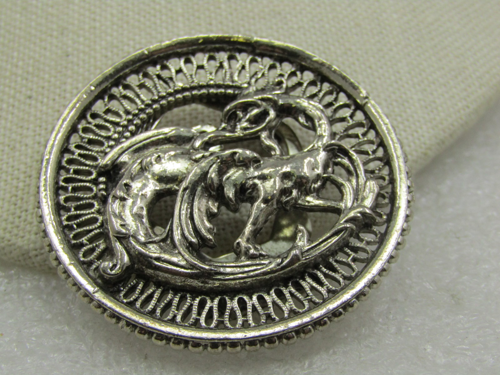 Early Black Pressed Metal Victorian Buckles: Vintage Dragon Brooch, Scarf Clip, 1-7/8" Round, Silver Tone, 1960's-1970's. Signed Art, The repousse dragon is covering the center of the brooch with a filigree frame and a raised dotted outer frame.