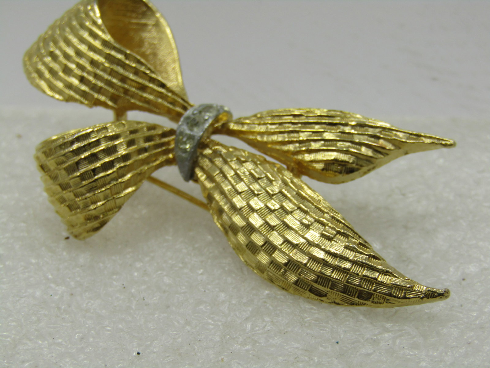 Vintage Gerry's Textured Looped Bow Brooch, With Rhinetones, 1960's: Vintage Gerry's Textured Looped Bow Brooch, With Rhinetones, 1960's. 2.75" tall and appx. 1-3/8" wide. Gold tone with a gextured woven design. It has a center wrap that is silver tone with clear