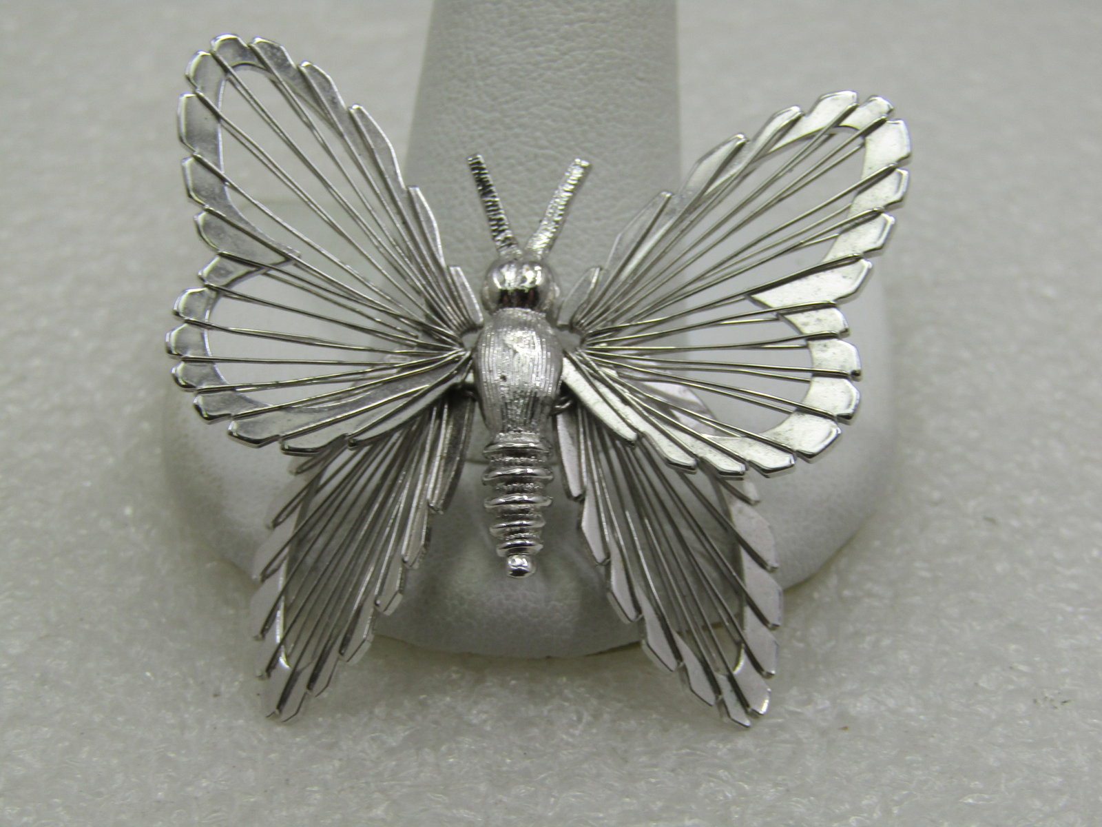 Vintage Monet Wire Winged Butterfly Brooch, 1960's-1970's: Vintage Monet Wire Winged Butterfly Brooch, 1960's-1970's. Silver Tone w ith tiered wings and a textured torso. The brooch is appx. 1.5" tall and 1.75" wide. Silver tone, bright and shiny wings. Signe