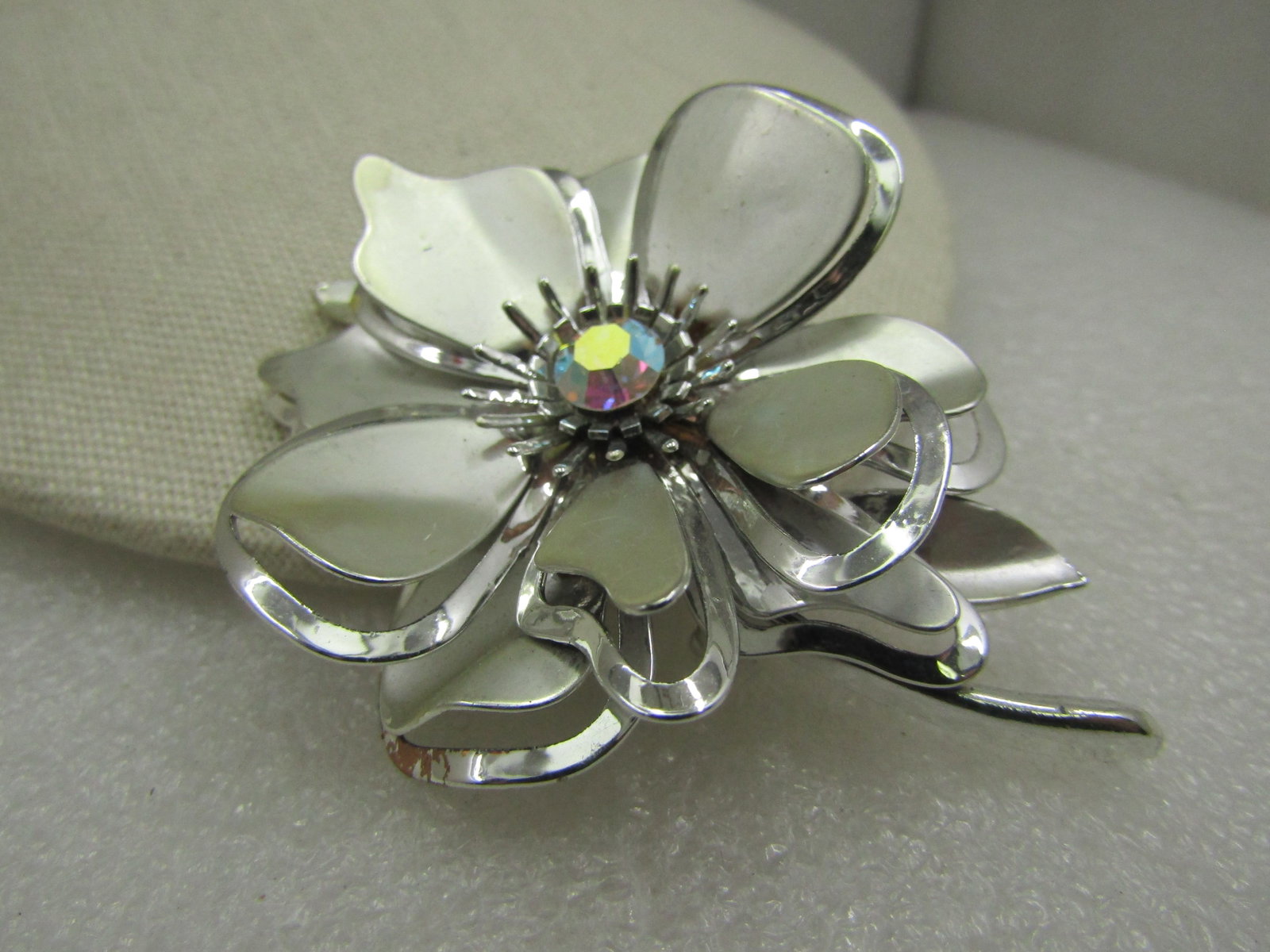 Vintage Silver Tone Floral Brooch, Aurora Borealis Rhinestone, 1960's: Vintage Silver Tone Floral Brooch, Aurora Borealis Rhinestone, 1960's It is3" by 2.5". Silver tone with satiny and smooth finish. Two tiers of petals that are curved and have a smooth outline frame an