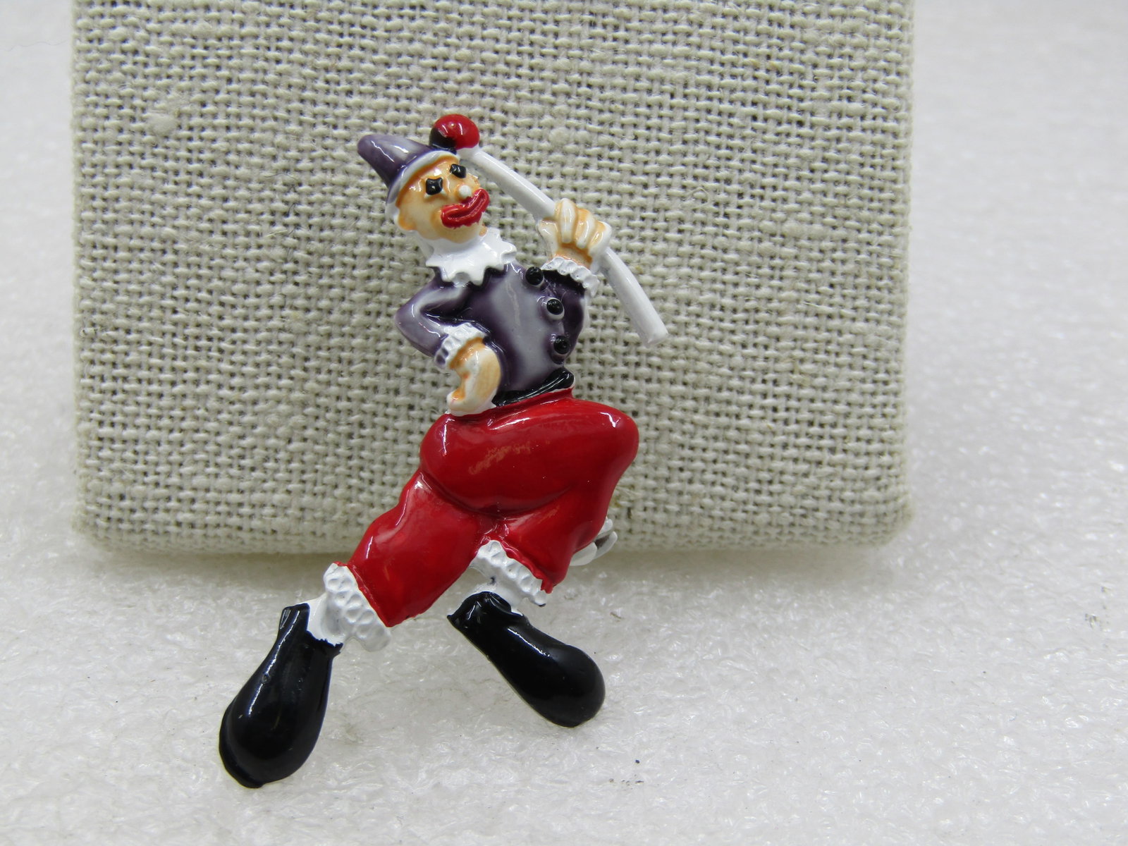 Vintage Enameled Clown Brooch, 2", On Card: Vintage Enameled Clown Brooch, 2" tall and 1" wide, On Card. It is enameled with black shoes and charcoal sshirt and cap with red pants and mouth holding a red and white baton with white enameled ruff