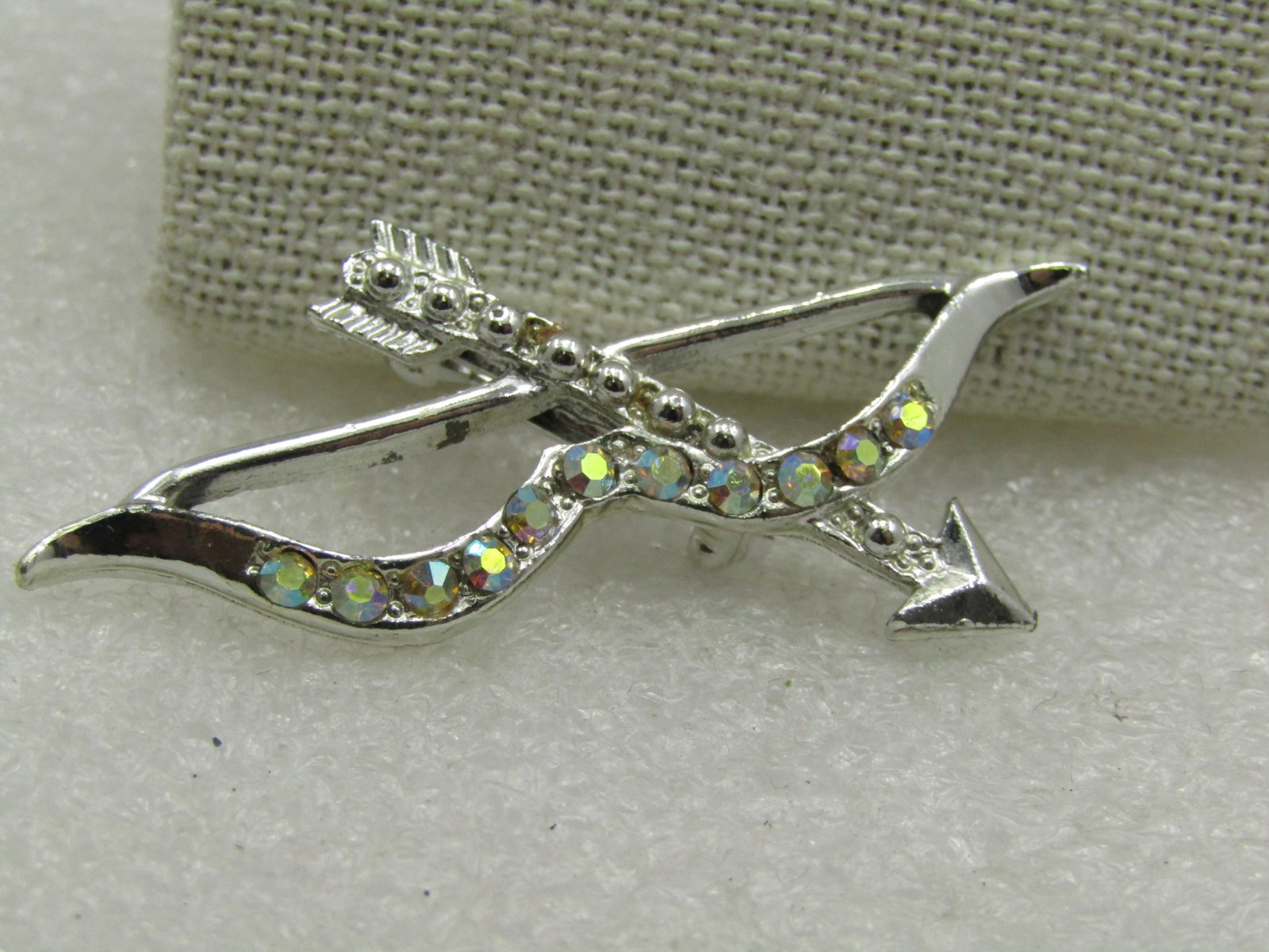 Vintage Aurora Borealis Rhinestone Bow Arrow Brooch. 2", 1950's-1960's.: Vintage Aurora Borealis Rhinestone Bow Arrow Brooch. 2" tall and 1.25" wide. Cupid's bow and arrow signifying love. The rhinestones are set in the frame of the bow with rounded accents in the arrow. S